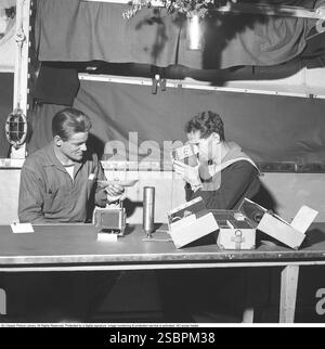 Swedish sailors in the Swedish navy in 1942. One of the sailors is holding up a model of a sailing ship that looks only just begun, while the other is filming with a film camera. They are sitting in one of the ship's rooms where the crew can do other things when they are not on duty. Kristoffersson ref A63-3 Stock Photo