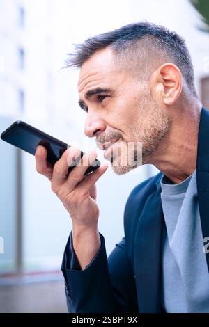 Businessman Using Voice Command on Smartphone Outdoors.Vertical Stock Photo