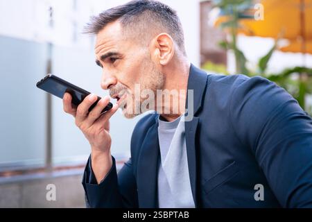 Businessman Using Voice Command on Smartphone Outdoors Stock Photo