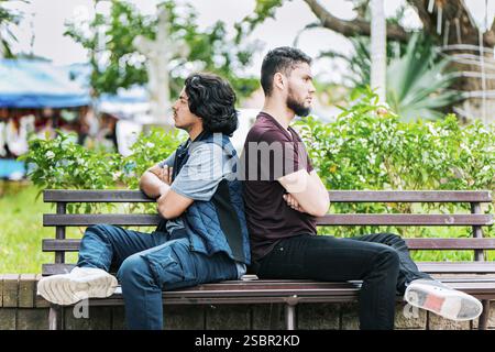 Two friends arguing on a park bench. Two angry friends sitting on a park bench Stock Photo