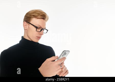 Focused young man wearing glasses interacts with his smartphone in a sleek, illuminated environment. Stock Photo