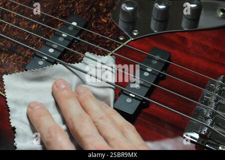 Cleaning and Polishing Electric Bass Guitar with Microfiber Cloth – Instrument Care and Maintenance Stock Photo