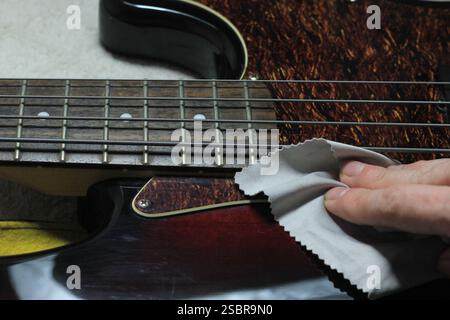 Cleaning and Polishing Electric Bass Guitar with Microfiber Cloth – Instrument Care and Maintenance Stock Photo