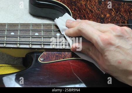 Cleaning and Polishing Electric Bass Guitar with Microfiber Cloth – Instrument Care and Maintenance Stock Photo