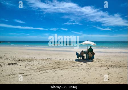 Relaxing Beach Scene with People Under Umbrella by the Bright Blue Sea in The Bahamas. Stock Photo