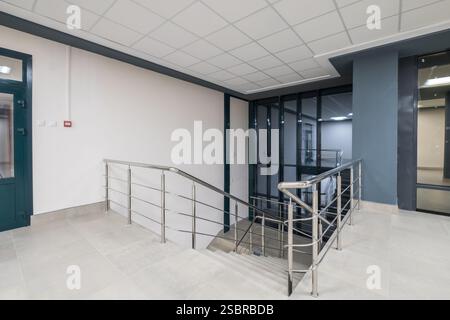 panorama view in empty modern office hall with columns, doors, stairs and panoramic windows at night Stock Photo