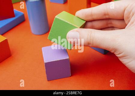Hand building tower with colorful building blocks Stock Photo