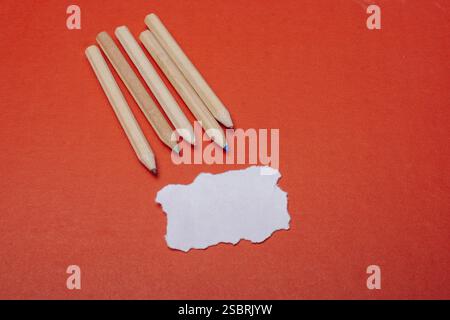 Colored pencils on red background and and torn paper Stock Photo