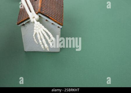 Small model house and human skeleton hand as horror concept Stock Photo