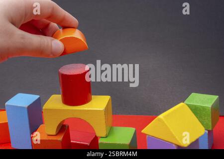 Hand building tower with colorful building blocks Stock Photo