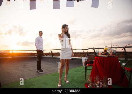 Romantic rooftop sunset dinner with elegant table setting and couple enjoying the moment Stock Photo