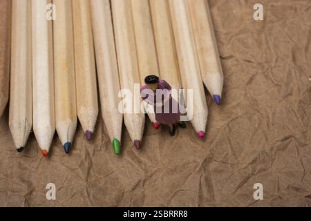 Colored pencils on paper background with a woman figurine Stock Photo