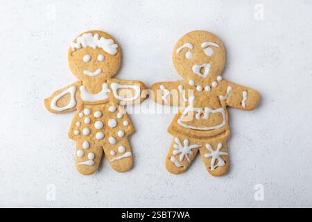 Two gingerbread men decorated with white icing. Traditional New Year and Christmas homemade cookies on a white background. Selective focus, close-up. Stock Photo