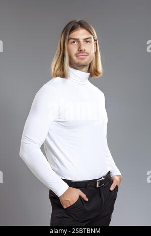 Male fashion, beauty concept. Portrait of young man with blond hair, posing over gray background. Classic style. Studio shot Stock Photo