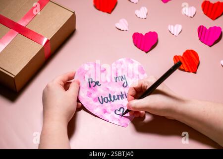 Woman creating valentines day card. Greeting card with phrase "Be my valentine". Valentines day concept. Stock Photo