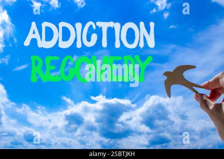 Addiction recovery symbol. Concept words Addiction recovery on beautiful blue sky. Psychologist hand, wooden bird. Beautiful blue sky cloud background Stock Photo