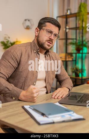 Sad Caucasian businessman looks pensive thinks over life concerns or unrequited love, suffers from unfair situation. Problem, break up, depressed feeling bad, burnout. Guy at home office at table. Stock Photo