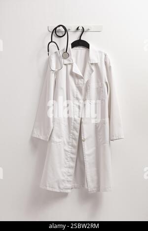 Doctors lab coat and stethoscope handing on a wall isolated on white background Stock Photo