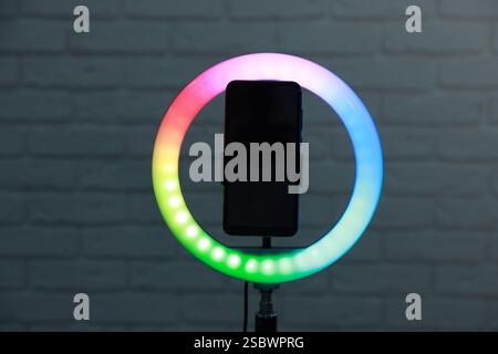Ring lamp with smartphone against brick wall Stock Photo