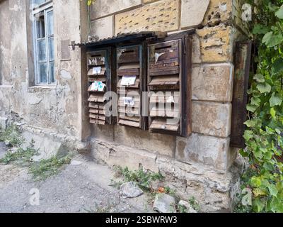 Group of old rusty mailboxes on the weathered stone wall of a residential building Stock Photo