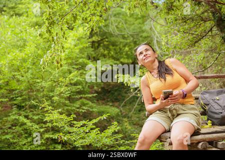 Woman using smartphone for pathfinding in forest Stock Photo