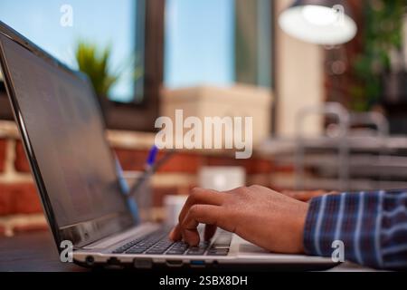 Selective focus of african american person typing on laptop, inputting project data at office desk. Closeup on hands of black male individual using digital device keyboard, searching on internet. Stock Photo