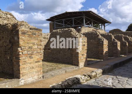 Old terracotta brick and stone building structures and walls plus street surface made of large grey smooth and worn lava stones at the ancient ruins o Stock Photo