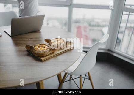 Bread dishes on a table with a laptop and chair in a modern space Stock Photo