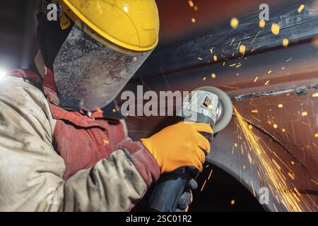 Close-up of a worker using an angle grinder on metal, with sparks Stock Photo