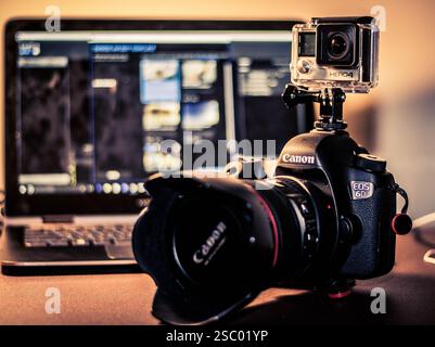 Camera equipment is arranged on a table with a laptop nearby. Stock Photo