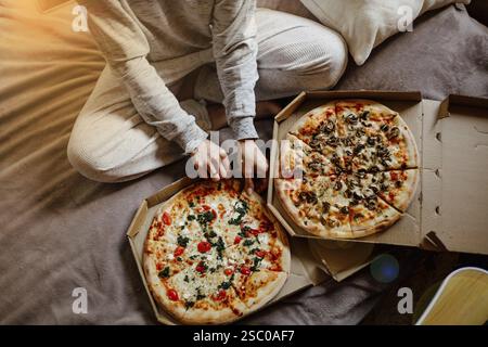 Person in pajamas enjoying pizza in bed Stock Photo