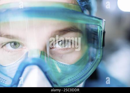 Healthcare worker wearing protective goggles and mask, focused look in a detailed close-up Stock Photo