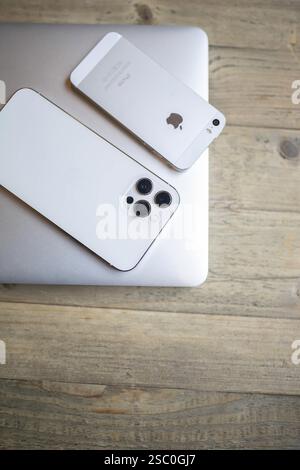 White iPhone with a visible camera module on a wooden table Stock Photo