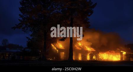 House engulfed in flames at night with a dark sky background Stock Photo