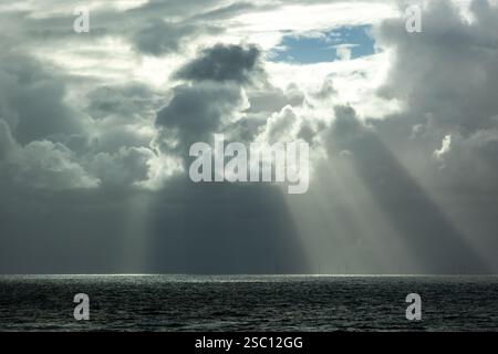 Cloudscape over the sea short before a thunderstorm and rain with sunrays shining through dark clouds Stock Photo