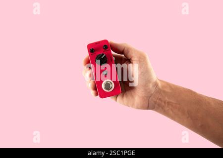 Male hand holding a pink guitar effects pedal isolated on pink background cutout Stock Photo