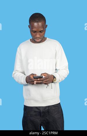 Young man using smartphone on blue background: concentrated man browsing social media Stock Photo
