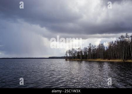 Dramatic storm over a dark lake. Ominous clouds and choppy water create a powerful and intense scene. Perfect for weather, nature, or dramatic landsca Stock Photo