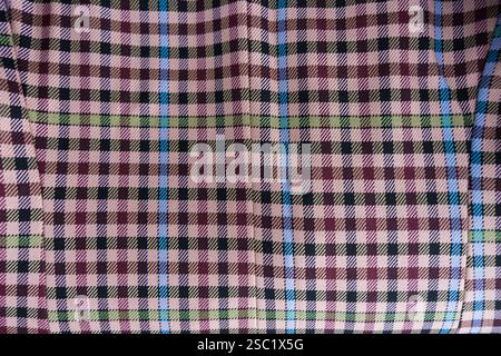 A detailed view of checkered fabric featuring pink, maroon, green, blue, and beige tones.  Stock Photo