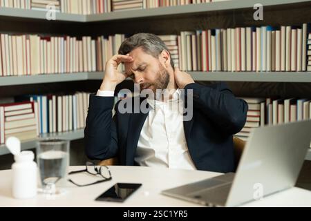Sad business man having a terrible headache. Exhausted man feeling unhealthy, upset about headache illness. Stressed middle-aged man having headache. Stock Photo