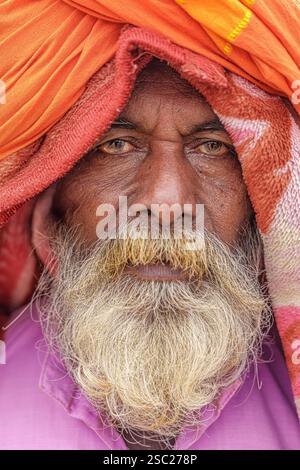 A close-up headshot of a bearded Sadhu, his face calm and focused, with blankets draped above his head, symbolizing peace and spiritual solitude. Stock Photo