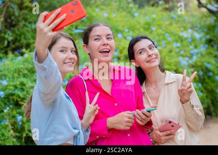 Three Happy Women Taking a Selfie in a Green Park Stock Photo