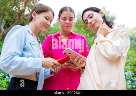 Three Young Women Using Smartphones Outdoors Stock Photo