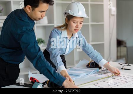 Diverse architects measuring and reviewing construction design plans. Stock Photo