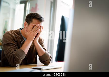 Portrait of a disappointed man programmer looking stressed out while working on a computer code Stock Photo