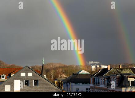colorful rainbow over the city with a dramatic gray rainy sky Stock Photo