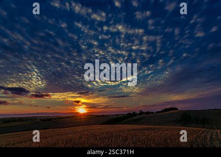 Beautiful sunset with wavy clouds over cultivated fields in the Danish countryside. Denmark, Europe Stock Photo