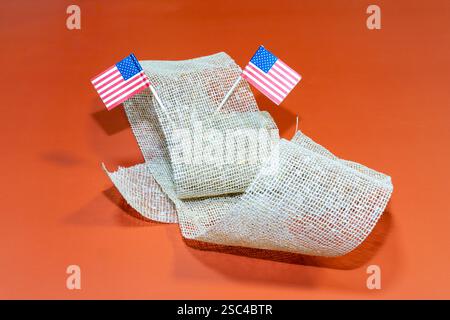 Small American flags on a brown fabric with an orange background Stock Photo