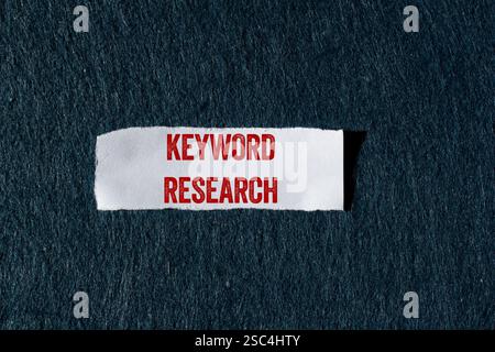 Keyword research message written on ripped torn paper piece with gray background. Conceptual keyword research symbol. Copy space. Stock Photo