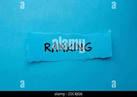 Ranking message written on ripped torn paper piece on blue background. Conceptual ranking symbol. Copy space. Stock Photo